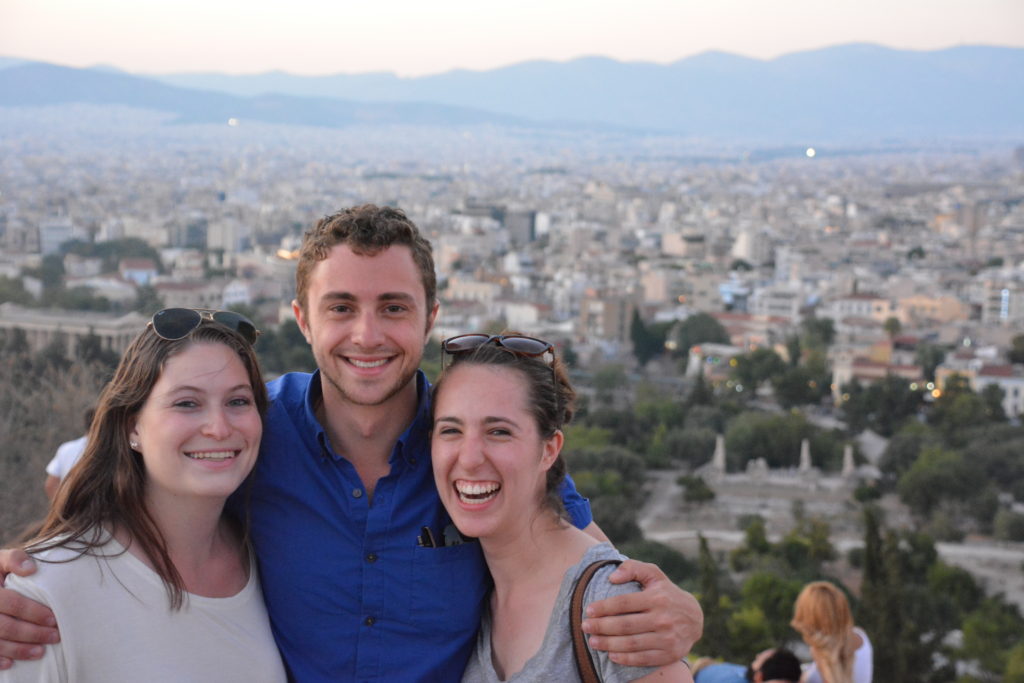 Three students in front of a city skyline